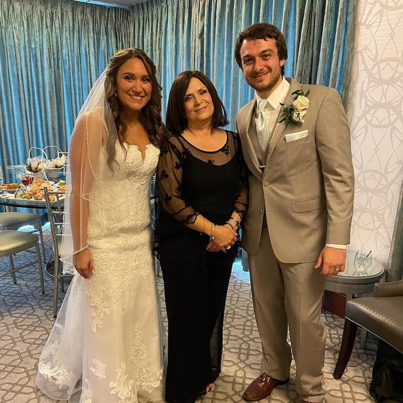 A bride and groom posing for a photo in a hotel room with their long island wedding officiant.