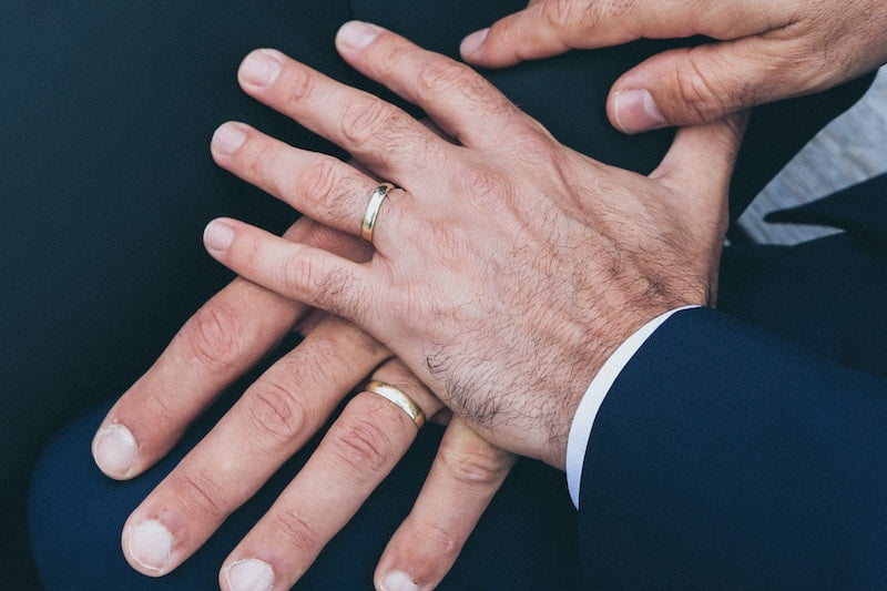 Two men's hands holding each other's wedding rings with long island wedding officiants.