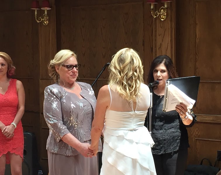 A long island wedding officiant guides a bride and groom as they exchange vows in front of a group of people.