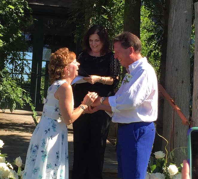 A long island officiant is facilitating the exchange of vows between a man and woman in a beautiful garden setting.