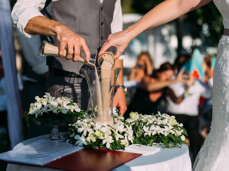 A bride and groom, joined by a Long Island wedding officiant, pouring a drink into a glass.