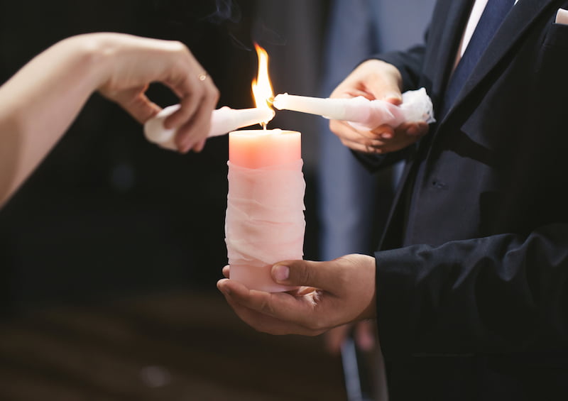 Long Island wedding officiants guiding a man and woman as they light a candle at a wedding.