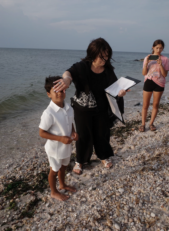 A woman and a boy standing on the beach, joined by a Long Island officiant.